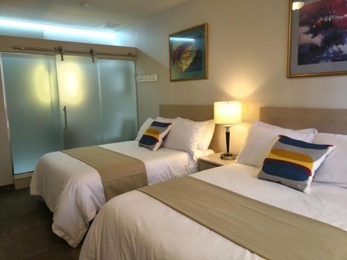 a hotel room with two beds and a lamp at Hotel Le Deville in Montreal