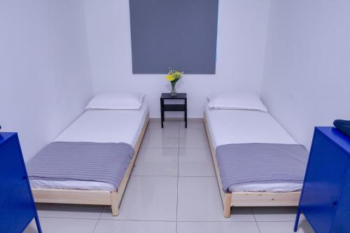 three beds in a room with a vase on a table at The Khailily's Guest in Sepang