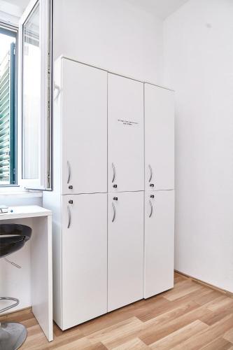 a row of white cabinets in a room with a window at Love Dubrovnik Hostel in Dubrovnik