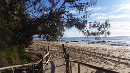 a sandy beach with a fence and the ocean at Forest view bungalow in Nambucca Heads