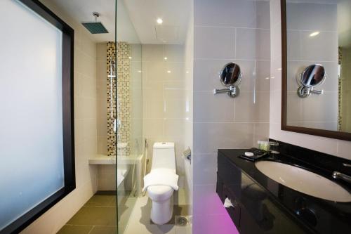 a bathroom with a toilet and a sink and a mirror at AnCasa Hotel Kuala Lumpur, Chinatown by AnCasa Hotels & Resorts in Kuala Lumpur