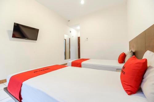 two beds with red pillows in a room at RedDoorz Plus at Karebosi Area 2 Makassar in Makassar