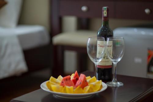 einen Obstteller, eine Flasche Wein und Gläser in der Unterkunft Spoon Hotel in Hanoi