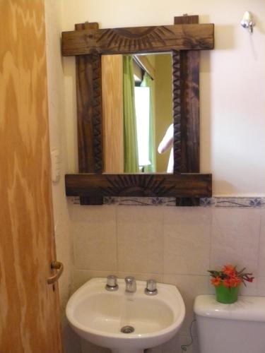 y baño con lavabo, espejo y aseo. en Hostal La Antigua en Humahuaca