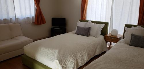 a bedroom with two beds and a chair and window at La Curación in Naoshima