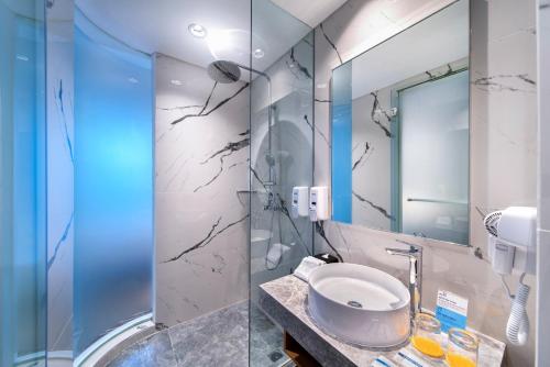 ein Bad mit einem Waschbecken und einem Spiegel in der Unterkunft Holiday Inn Express Jakarta Matraman, an IHG Hotel in Jakarta