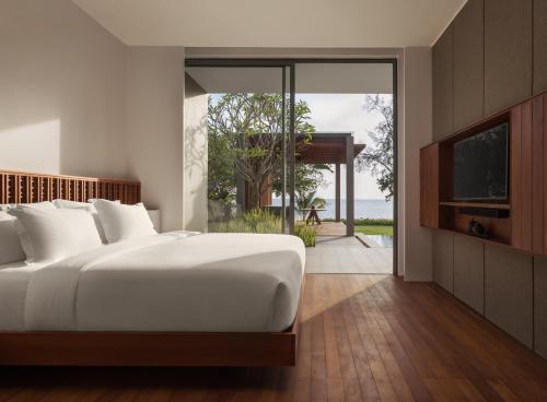 a bedroom with a large white bed and a sliding glass door at Koh Russey Resort in Koh Russey