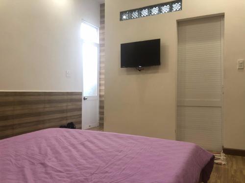 um quarto com uma cama e uma televisão na parede em Ruby Dalat Hostel em Da Lat