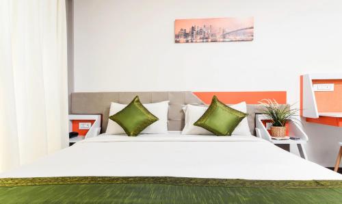 a bedroom with a large white bed with green pillows at Treebo Stay Tuned JP Nagar in Bengaluru