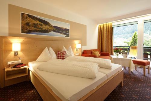 a hotel room with two beds and a large window at Familiengut Hotel Burgstaller in Döbriach