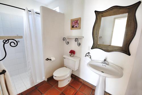 a bathroom with a toilet and a sink and a mirror at Los Milagros Hotel in Cabo San Lucas