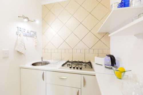 a white kitchen with a stove and a sink at Ocean Breeze Bloubergstrand in Bloubergstrand