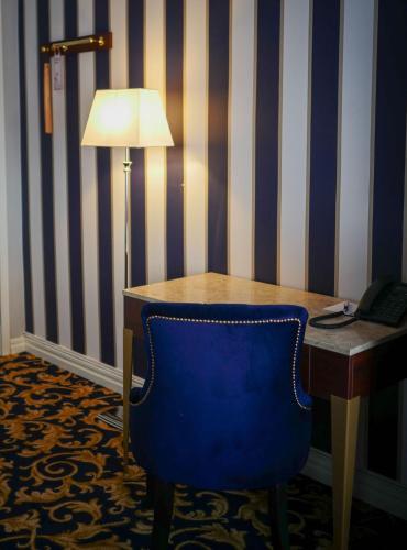 a desk with a blue chair next to a table with a lamp at Hotel Gamla Stan, BW Signature Collection in Stockholm