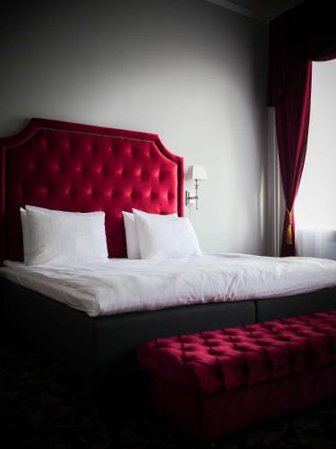 a bed with a red headboard and a red bench at Hotel Gamla Stan, BW Signature Collection in Stockholm