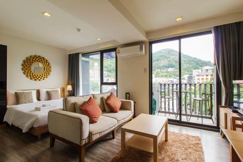 a bedroom with a bed and a couch and a balcony at The Deck Condominium Patong Beach in Patong Beach