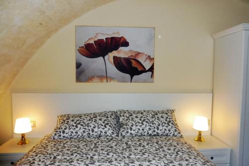 a bedroom with a bed with two flowers on the wall at La Ginestra Affittacamere in Ginosa