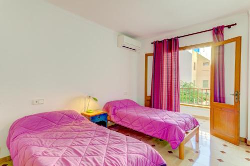 two beds in a bedroom with pink sheets and a window at Emma Beachfront Apartment in Port de Pollensa