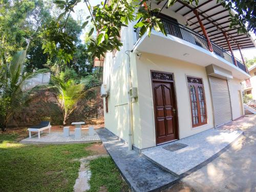 a white house with a wooden door and a bench at Villa Girilena in Hikkaduwa