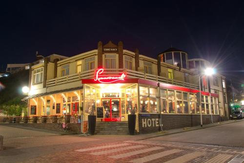 a hotel with a neon sign in front of it at night at Sonnevanck Wijk aan Zee in Wijk aan Zee