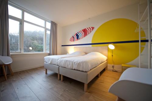 ein Schlafzimmer mit einem Bett mit einer gelben und blauen Wand in der Unterkunft Sonnevanck Wijk aan Zee in Wijk aan Zee
