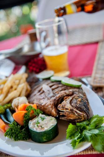 a plate of food with meat and vegetables and a glass of beer at Hotel Tilapia in Mwanza