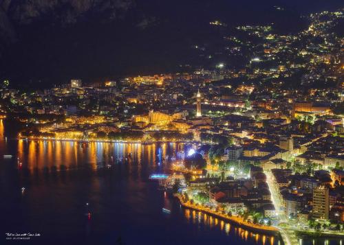 a city at night with lights on the water at Fall In Love with Como Lake in Bellano