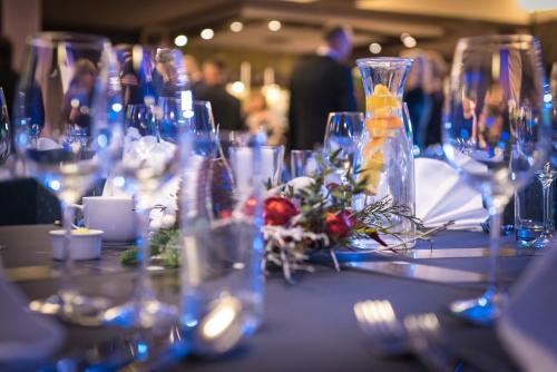 a table with wine glasses and flowers on it at Hotel Tigra in Priekuļi