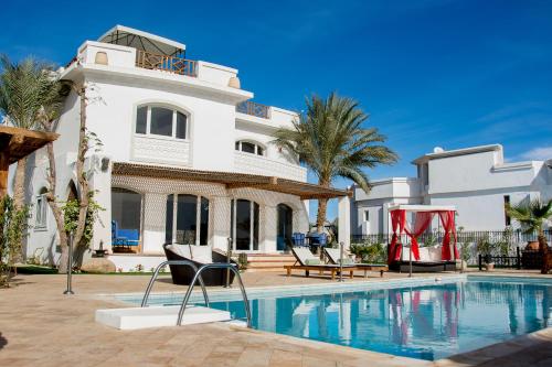 a villa with a swimming pool in front of a house at Jacaranda in Sharm El Sheikh