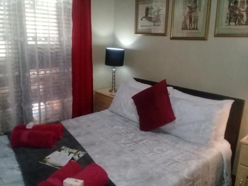 a bedroom with a bed with red and white pillows at The Buddha Garden in Cape Town