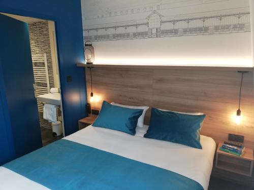 a bedroom with a large bed with blue pillows at Hôtel des Halles in Dijon