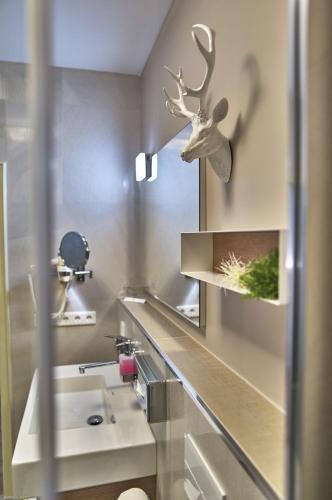 a bathroom with a sink and a deer head on the wall at Hotel Lindenhof in Kellberg