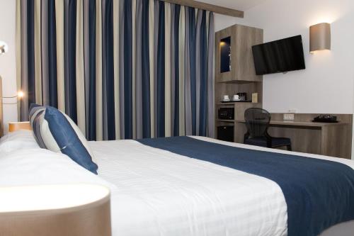 a hotel room with a bed and a tv at Le Domaine des Oliviers in Pierrelatte