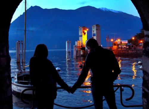 a couple holding hands in front of a body of water at Fall In Love with Como Lake in Bellano