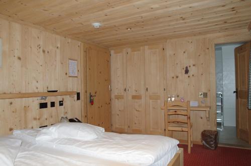 a bedroom with a bed and a wooden wall at Posthotel Rössli in Gstaad