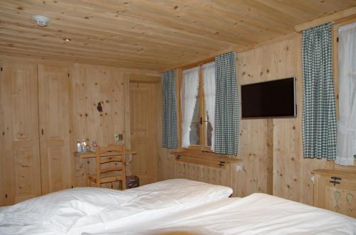 a bedroom with a bed and a tv on a wall at Posthotel Rössli in Gstaad