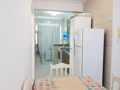 cocina con nevera, mesa y sillas en Residencial Júnior, en Bombinhas