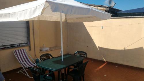 a table and chairs with an umbrella on a balcony at Beach House in Torvaianica