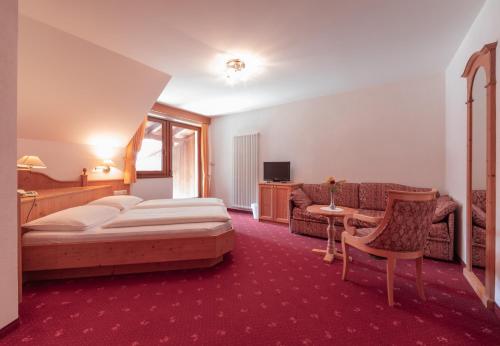 a hotel room with a bed and a couch at Berghotel zum Zirm in Collalbo