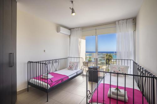 1 Schlafzimmer mit 2 Betten mit rosa Bettwäsche und einem Fenster in der Unterkunft Protaras Fig Tree Bay Suite in Protaras