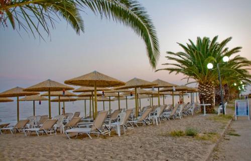 a row of chairs and umbrellas on a beach at Hotel Horizontas in Nea Plagia