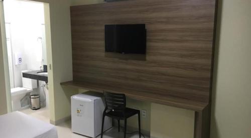 a room with a chair and a television on a wall at ALENCAR HOTEL in Barreiras