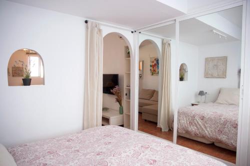 トレモリノスにあるLas Plumas Beachの白いベッドルーム(ベッド1台、鏡付)