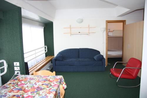 ein Wohnzimmer mit einem blauen Sofa und einem roten Stuhl in der Unterkunft Albaré Solaria Montana in Marilleva