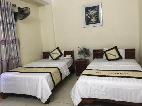 two beds in a room with white sheets at Tuan Minh Guest House in Diện Biên Phủ