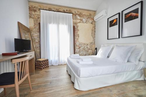 a white bedroom with a large bed and a television at Alqueria de Vilches in Cullera