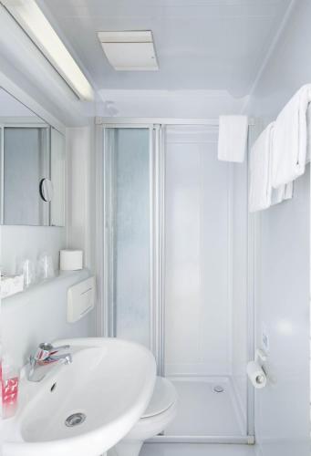 a white bathroom with a shower and a sink at Hotel Moerser Hof in Moers