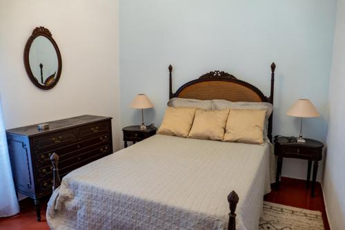 a bedroom with a bed and a mirror and a dresser at Quintal d'Angra in Angra do Heroísmo