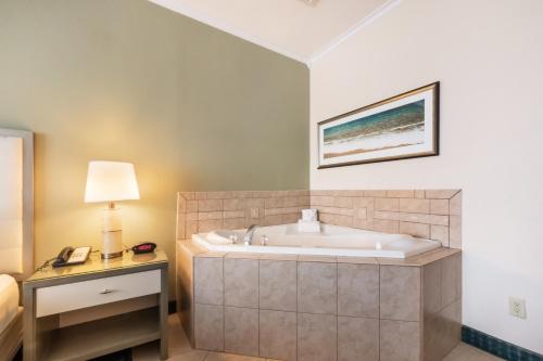 La salle de bains est pourvue d'une baignoire, d'un lit et d'une lampe. dans l'établissement Quality Inn & Suites Conference Center, à Winter Haven