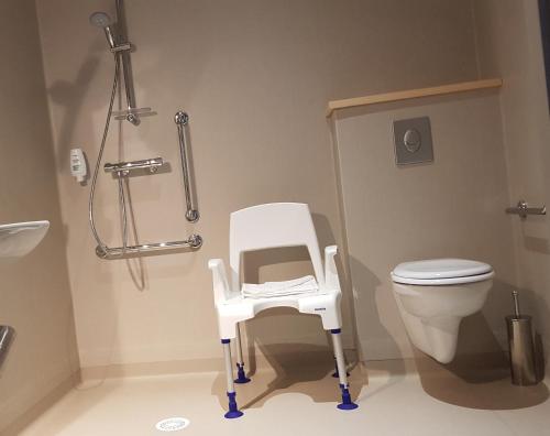 einen weißen Stuhl im Bad mit WC in der Unterkunft le tisseur des saveurs in Panissières