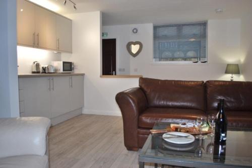 a living room with a brown leather couch and a table at Gallowgate Square Apartments in Largs